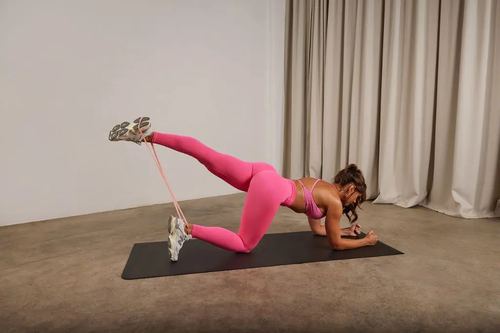 Kelsey Wells resistance band glute kickbacks
