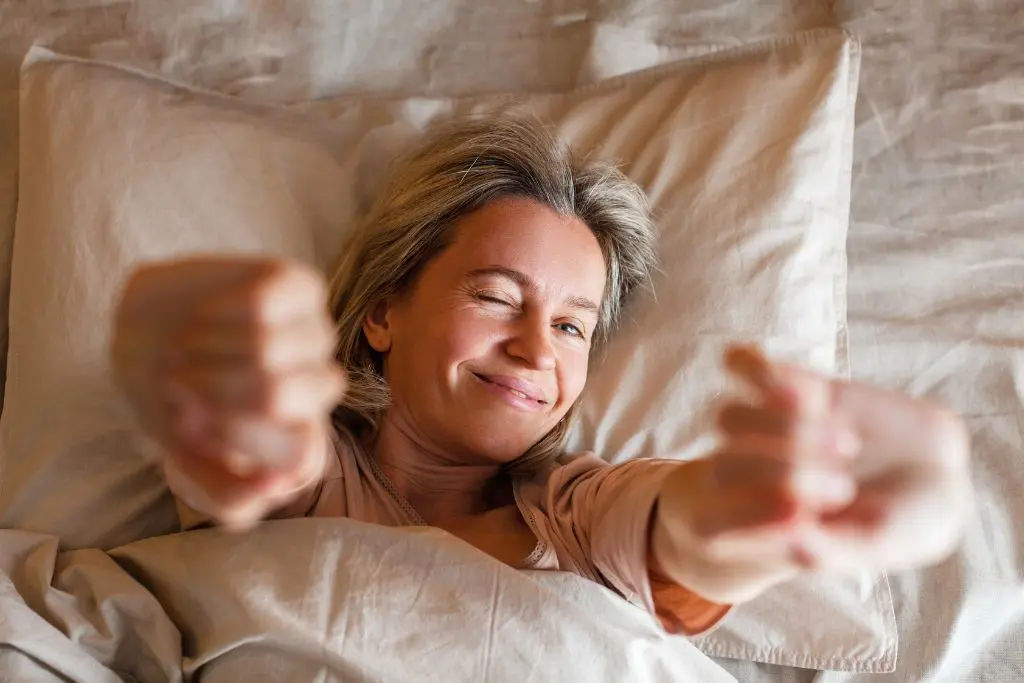 Woman in bed smiling and stretching